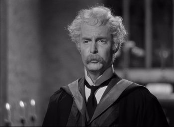 Movie still from “Goodbye, Mr. Chips” (1939), directed by Sam Wood – An older man in a graduation gown and tie; Close Up shot, Over the shoulder angle
