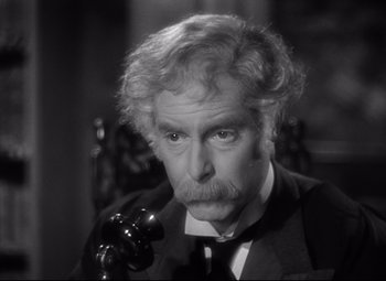 Movie still from “Goodbye, Mr. Chips” (1939), directed by Sam Wood – An older man in a suit and tie talking on a phone; Close Up shot, High angle