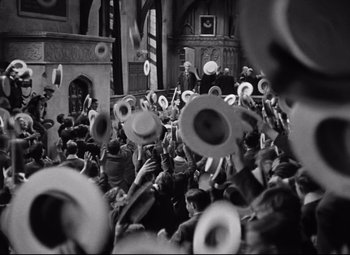 Movie still from “Goodbye, Mr. Chips” (1939), directed by Sam Wood – A group of people in a room with hats on their heads; Wide shot, High angle
