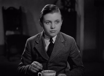 Movie still from “Goodbye, Mr. Chips” (1939), directed by Sam Wood – A young man in a suit and tie holding a cup of coffee; Close Up shot, High angle