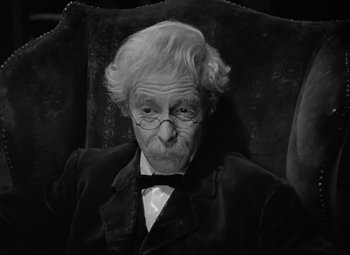 Movie still from “Goodbye, Mr. Chips” (1939), directed by Sam Wood – An old man sitting in a chair wearing glasses; Close Up shot, High angle