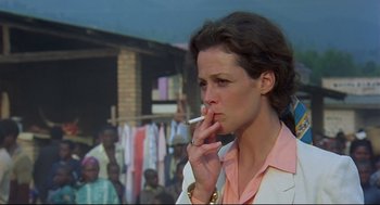 Movie still from “Gorillas in the Mist” (1988), directed by Michael Apted – A woman smoking a cigarette in front of a crowd of onlookers; Close Up shot, Low angle