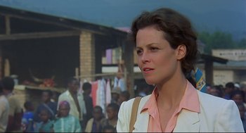 Movie still from “Gorillas in the Mist” (1988), directed by Michael Apted – A person with a crowd of people in the background; Close Up shot, Over the shoulder angle