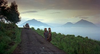 Movie still from “Gorillas in the Mist” (1988), directed by Michael Apted – A group of people walking down a dirt road; Extreme Wide shot, High angle