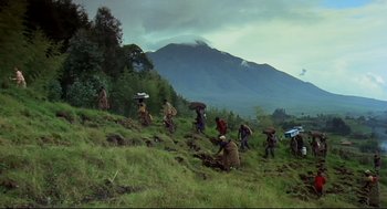Movie still from “Gorillas in the Mist” (1988), directed by Michael Apted – A group of people walking across a lush green hillside; Extreme Wide shot, High angle