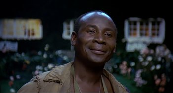 Movie still from “Gorillas in the Mist” (1988), directed by Michael Apted – A person smiling for the camera; Close Up shot, Over the shoulder angle