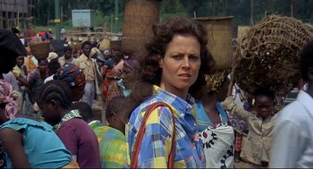 Movie still from “Gorillas in the Mist” (1988), directed by Michael Apted – A group of people standing in a crowd of men and women; Close Up shot, Over the shoulder angle