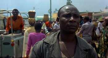 Movie still from “Gorillas in the Mist” (1988), directed by Michael Apted – A black man standing in front of a group of people; Close Up shot, Low angle