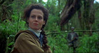 Movie still from “Gorillas in the Mist” (1988), directed by Michael Apted – A woman in a brown jacket standing next to a tree; Close Up shot, Low angle