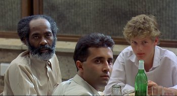 Movie still from “Gorillas in the Mist” (1988), directed by Michael Apted – A group of people sitting around a table; Close Up shot, Low angle