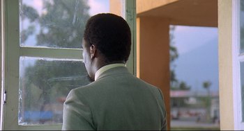 Movie still from “Gorillas in the Mist” (1988), directed by Michael Apted – A man wearing a suit looking out a window; Close Up shot, Over the shoulder angle