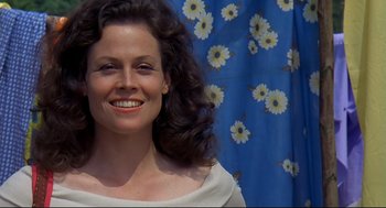 Movie still from “Gorillas in the Mist” (1988), directed by Michael Apted – A woman with long black curly hair smiles for the camera; Close Up shot, Low angle