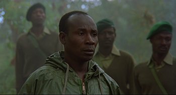 Movie still from “Gorillas in the Mist” (1988), directed by Michael Apted – A group of men standing next to each other in a forest; Close Up shot, Low angle