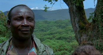 Movie still from “Gorillas in the Mist” (1988), directed by Michael Apted – A man standing next to a tree in the middle of a forest; Close Up shot, Low angle
