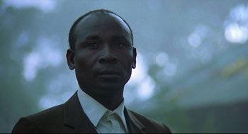 Movie still from “Gorillas in the Mist” (1988), directed by Michael Apted – A person wearing a suit and tie; Close Up shot, Low angle