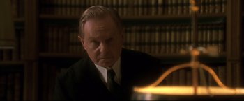 Movie still from “Gosford Park” (2001), directed by Robert Altman – An older man wearing a suit and tie in front of a book shelf; Close Up shot, Low angle