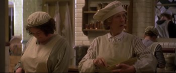 Movie still from “Gosford Park” (2001), directed by Robert Altman – A woman wearing a chef's hat in a kitchen; Close Up shot, Over the shoulder angle
