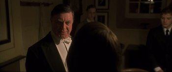 Movie still from “Gosford Park” (2001), directed by Robert Altman – An older man wearing a white bow tie; Medium shot, Over the shoulder angle