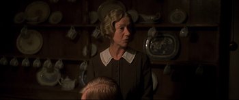 Movie still from “Gosford Park” (2001), directed by Robert Altman – An older woman in a brown and white dress; Medium shot, Over the shoulder angle