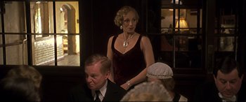 Movie still from “Gosford Park” (2001), directed by Robert Altman – An older woman in a red dress and a man in a black suit; Medium shot, Over the shoulder angle
