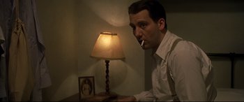 Movie still from “Gosford Park” (2001), directed by Robert Altman – A man sitting at a table in front of a lamp; Close Up shot, Low angle