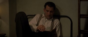 Movie still from “Gosford Park” (2001), directed by Robert Altman – A man sitting on a bed looking down at his cell phone; Medium shot, High angle