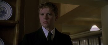 Movie still from “Gosford Park” (2001), directed by Robert Altman – A man in a suit and tie looking at the camera; Close Up shot, Low angle