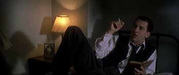 Movie still from “Gosford Park” (2001), directed by Robert Altman – A man sitting in a chair with a cigarette in his hand; Medium shot, Low angle