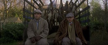 Movie still from “Gosford Park” (2001), directed by Robert Altman – A couple of men sitting next to each other in front of dead birds; Medium shot, Low angle