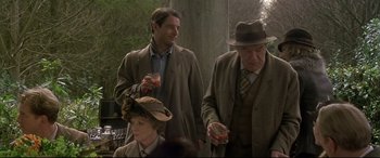 Movie still from “Gosford Park” (2001), directed by Robert Altman – Two men and a woman are standing together; Medium shot, Over the shoulder angle