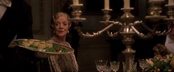 Movie still from “Gosford Park” (2001), directed by Robert Altman – A woman sitting in front of a table holding a plate; Close Up shot, Over the shoulder angle