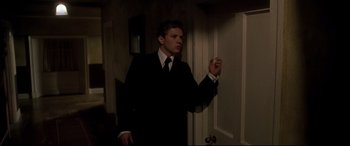 Movie still from “Gosford Park” (2001), directed by Robert Altman – A man wearing a suit and tie standing in a room; Medium shot, Low angle