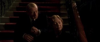 Movie still from “Gosford Park” (2001), directed by Robert Altman – An older man and a younger woman sitting next to each other; Medium shot, Low angle