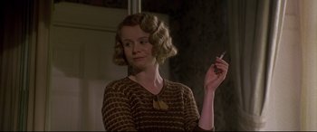 Movie still from “Gosford Park” (2001), directed by Robert Altman – A woman in a brown dress smoking a cigarette; Close Up shot, Low angle