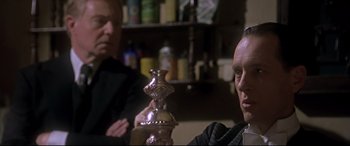 Movie still from “Gosford Park” (2001), directed by Robert Altman – A man sitting in front of another man holding a hookah pipe; Close Up shot, Over the shoulder angle
