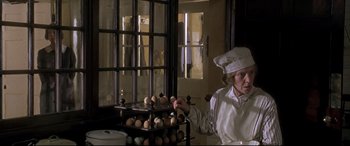 Movie still from “Gosford Park” (2001), directed by Robert Altman – A woman in a chef's hat and apron in front of a rack of eggs; Medium shot, Low angle