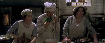 Movie still from “Gosford Park” (2001), directed by Robert Altman – A group of people standing in a kitchen eating food; Medium shot, High angle