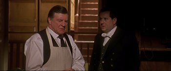 Movie still from “Gosford Park” (2001), directed by Robert Altman – Two men standing next to each other in front of a staircase; Medium shot, Over the shoulder angle