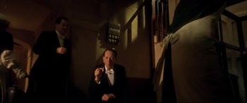 Movie still from “Gosford Park” (2001), directed by Robert Altman – A man in a suit and bow tie smoking a cigarette; Medium shot, Low angle
