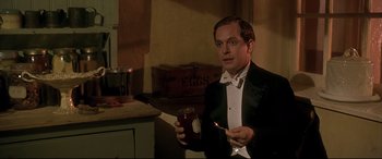 Movie still from “Gosford Park” (2001), directed by Robert Altman – A man in a tuxedo holding a jar and a knife; Medium shot, Low angle