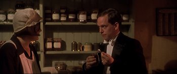 Movie still from “Gosford Park” (2001), directed by Robert Altman – A man in a suit and bow tie holding a jar; Close Up shot, Low angle
