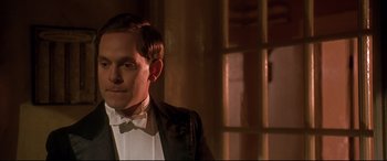 Movie still from “Gosford Park” (2001), directed by Robert Altman – A man in a tuxedo standing next to a window; Close Up shot, Low angle