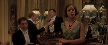 Movie still from “Gosford Park” (2001), directed by Robert Altman – A woman sitting at a table in front of two other people; Medium shot, Low angle