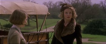 Movie still from “Gosford Park” (2001), directed by Robert Altman – A woman standing next to an old fashioned covered wagon; Medium shot, Low angle