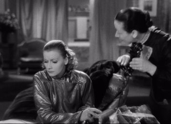 Movie still from “Grand Hotel” (1932), directed by Edmund Goulding – A woman sitting on the ground with another woman standing next to her; Medium shot, Over the shoulder angle