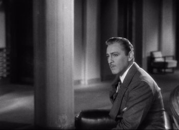 Movie still from “Grand Hotel” (1932), directed by Edmund Goulding – A man in a suit and tie sitting in a chair; Close Up shot, Over the shoulder angle