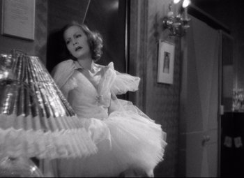 Movie still from “Grand Hotel” (1932), directed by Edmund Goulding – A black and white photo of a woman in a white dress; Medium shot, Low angle