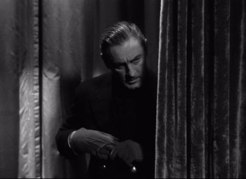 Movie still from “Grand Hotel” (1932), directed by Edmund Goulding – A black and white photo of a man holding a gun; Medium shot, Low angle