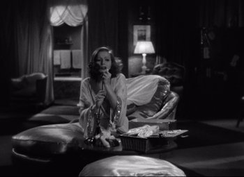 Movie still from “Grand Hotel” (1932), directed by Edmund Goulding – A black and white photo of a woman sitting on a couch; Medium shot, High angle