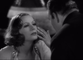 Movie still from “Grand Hotel” (1932), directed by Edmund Goulding – An old photo of a man putting lipstick on a woman; Close Up shot, Over the shoulder angle